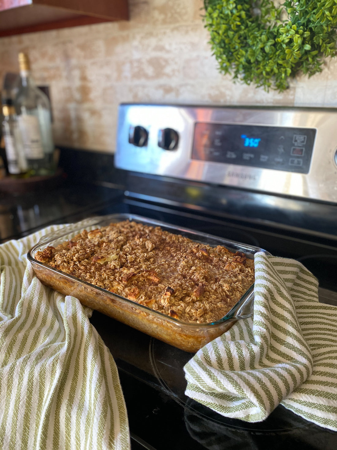 Baked oatmeal on black stovetop with green wreath hanging on wall above