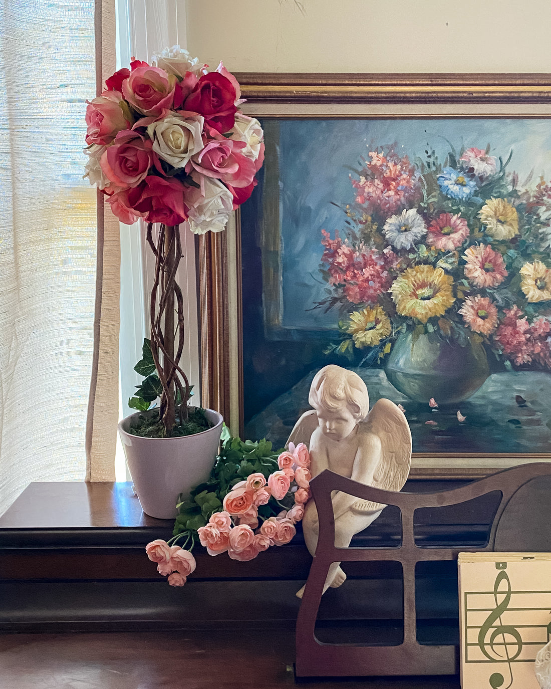 pink rose topiary and cherub statue on piano in front of floral painting